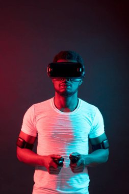 African Man in white, wearing VR Headset on red and blue dual color background. clipart