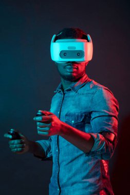 African Man in white, wearing VR Headset on red and blue dual color background. clipart