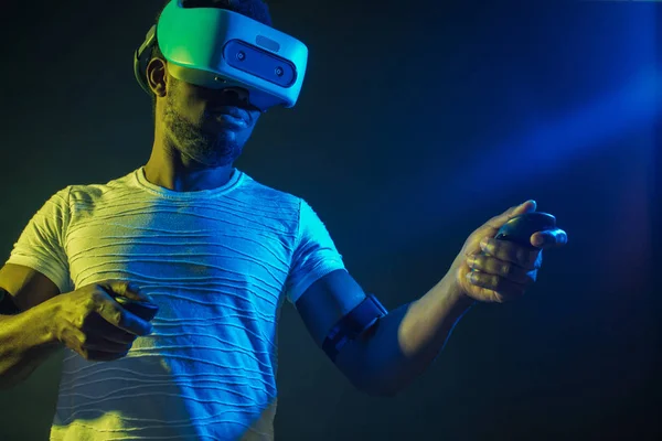 Uomo africano in bianco, indossando VR Headset su sfondo verde blu doppio colore . — Foto Stock