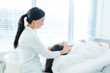 Güzeller güzeli genç kız güzellik salonunda yüz masajı yaptırıyor.