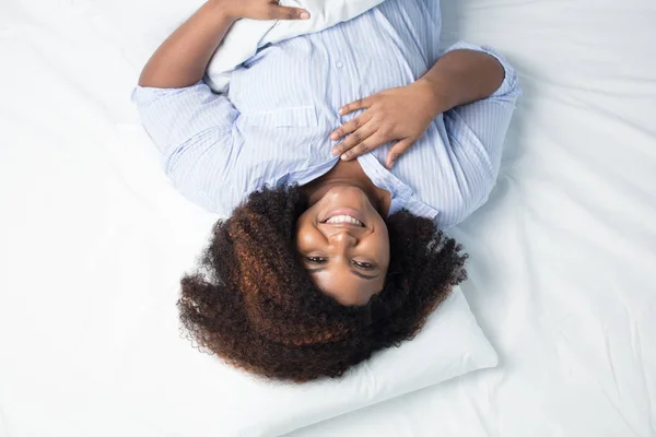 Šťastná žena s vlnité vlasy, ležící v posteli — Stock fotografie