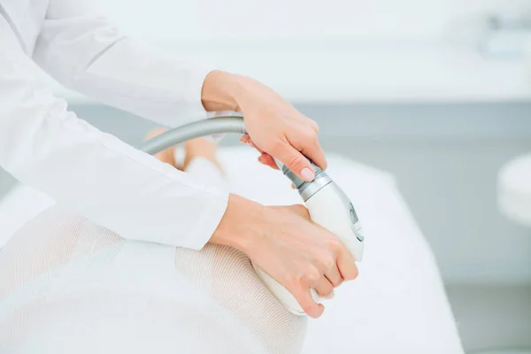 Donna in tuta bianca che ottiene la procedura GPL, trattamento del contorno del corpo in clinica . — Foto Stock