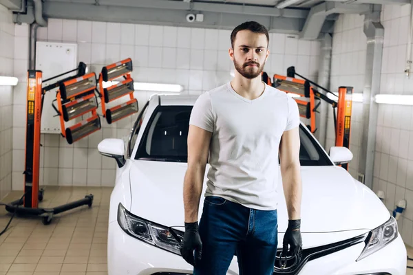 Seriös kille klädd i vit T-shirt och jeans tittar på kameran — Stockfoto