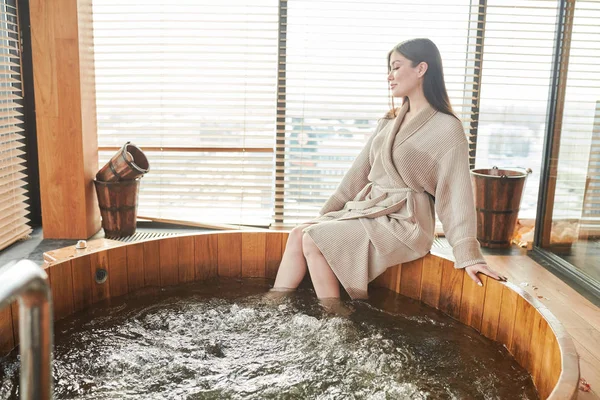 Brunetka kobieta relaksując się w jacuzzi w centrum spa z panoramicznymi oknami — Zdjęcie stockowe