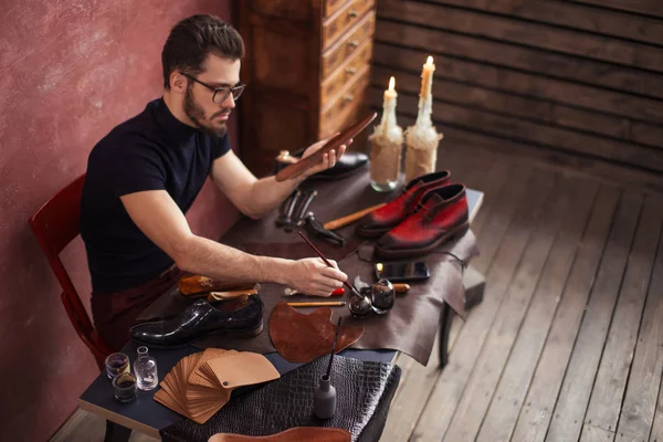 Homme sérieux peignant sur une paire de chaussures — Photo