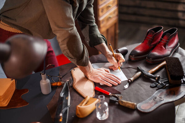 cobbers hands with a pencil on a desk