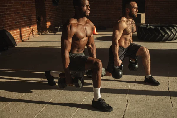 Dvě mnohonárodnostní atletů, takže výpady s hmotností v indoor trénink — Stock fotografie