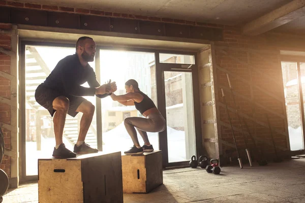 Man och kvinna hoppa tohether på lådor i gym, funcrional träning för personer — Stockfoto