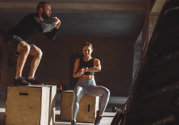Hombre y mujer saltando tohether en cajas en el gimnasio, entrenamiento funcrional para las personas — Foto de Stock