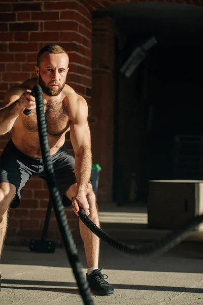 Junger kaukasischer Mann trainiert mit Kampfseilen in einem Fitnessstudio — Stockfoto