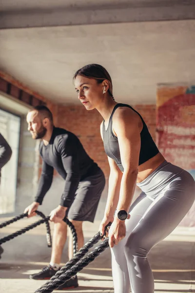 Γυναίκα και άντρας στο γυμναστήριο λειτουργική προπόνηση με μάχη σχοινί άσκηση — Φωτογραφία Αρχείου