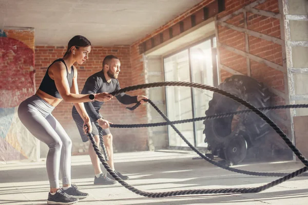 Mujer y hombre en el gimnasio entrenamiento funcional con ejercicios de cuerda de batalla — Foto de Stock