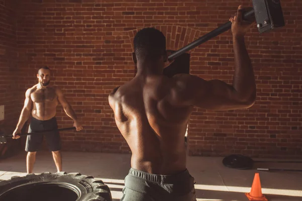 Sport fitness mannen raken wiel band met hamer slee, Cross fit training. — Stockfoto