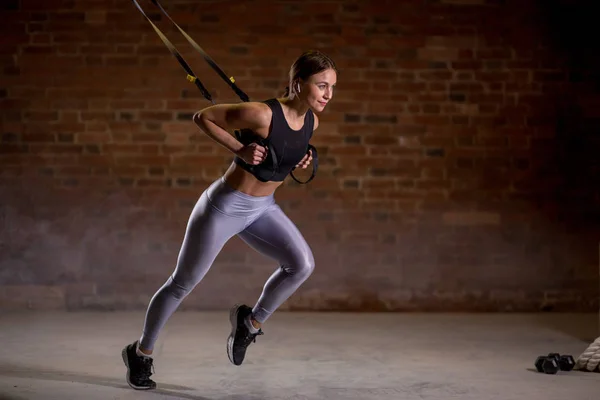 Fitness mulher treino em correias TRX no ginásio. Estilo Crossfit. Formação TRX . — Fotografia de Stock