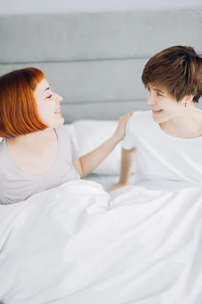 beautiful cheerful women laughing while sitting on bed. close up photo. happiness, free time