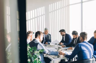Çok ırklı erkek işletme yöneticileri konferans masasında oturan projeyi tartıştılar