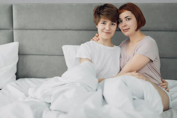 Hübsche Mädchen schauen in die Kamera, während sie im Bett sitzen — Stockfoto