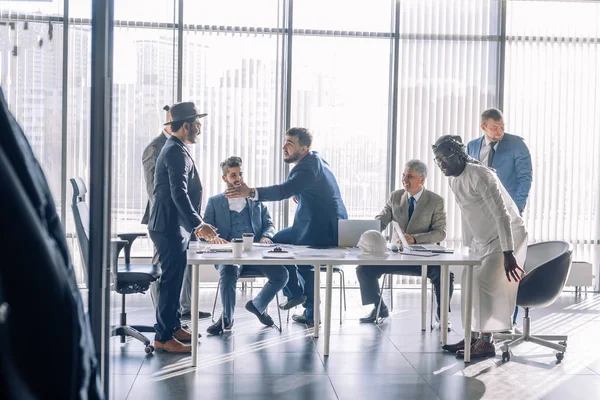 Multiracial male business executives discuss project sitting at conference table