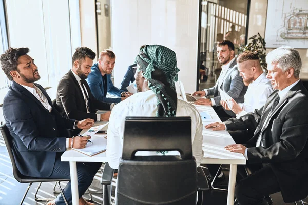 Leader arabo con la sua ambiziosa squadra seduta al tavolo — Foto Stock