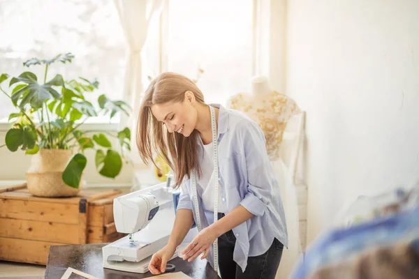 Mooie naaister werkt met een bruiloft jurk model in haar atelier — Stockfoto