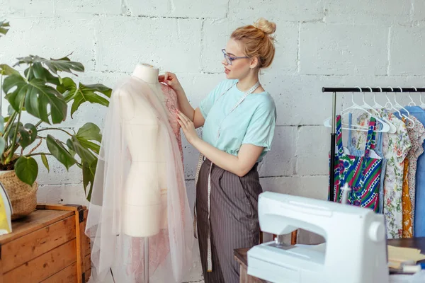 Mooie naaister werkt met een bruiloft jurk model in haar atelier — Stockfoto
