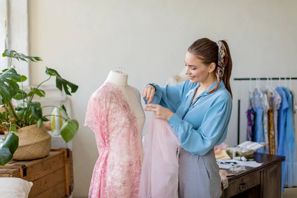 Linda costureira está trabalhando com um modelo de vestido de noiva em seu estúdio — Fotografia de Stock