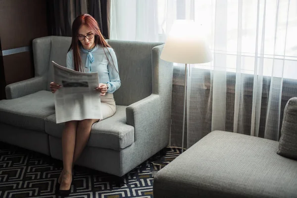 Happy young businesswoman reading newspaper in hotel lobby — Stock Photo, Image