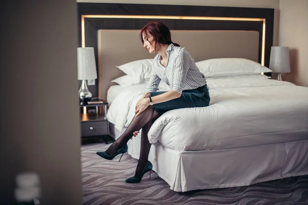 Företag dam att vara trött efter en lång resa som vilar på sängen på hotellrummet. — Stockfoto