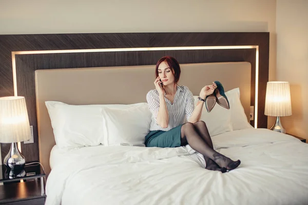 Элегантная стильная деловая женщина в туфлях на каблуках, лежащих на кровати в отеле — стоковое фото