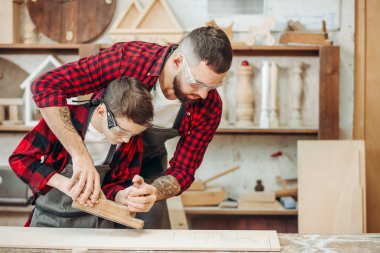 Oğlu ve uçak ahşap ile çalışırken kullanmak için yardımcı olur kucaklayan bir marangoz