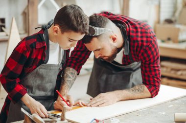 Cetvelli ve kalemli adamlar iş için tahta ölçüyorlar.