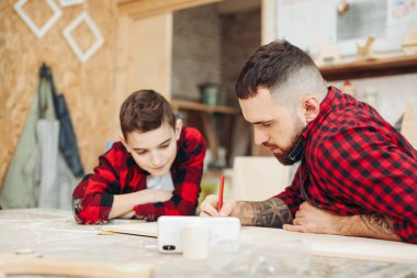 Baba ve oğul atölyede ahşap bir uçağın modelini tasarlıyorlar.