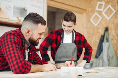 Baba ve oğul atölyede ahşap bir uçağın modelini tasarlıyorlar.