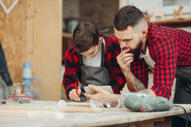 Baba ve oğul atölyede ahşap bir uçağın modelini tasarlıyorlar.