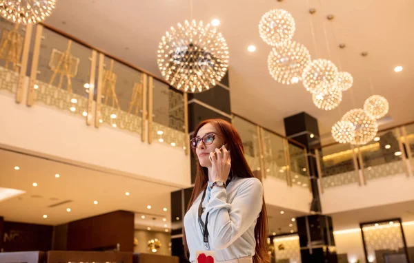 Foto de la joven mujer de negocios sonriente charlando en el teléfono inteligente en el hotel — Foto de Stock