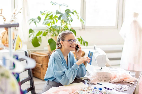 Mooie naaister dragen van stijlvolle blouse en brillen praten aan de telefoon — Stockfoto