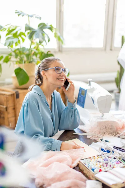 Mooie naaister dragen van stijlvolle blouse en brillen praten aan de telefoon — Stockfoto