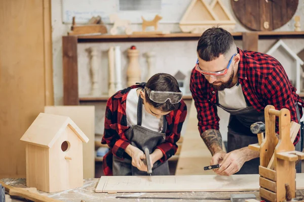 Father and his son working together in a wooden workshop, building a birdhouse — Stock Photo, Image