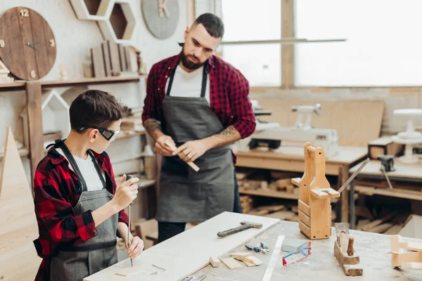 Baba ve küçük oğlu tornavida kullanarak ahşap atölyedeler..