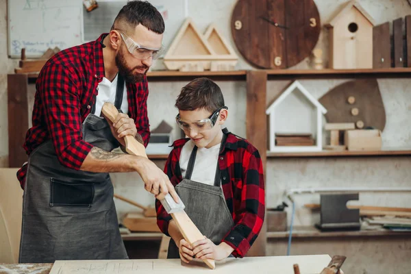 Father and son playing knights with wooden DIY swords at carpenter workshop