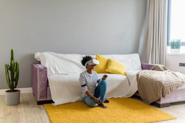 Afrikalı kadın izlerken video VR gözlükle evde uzaktan kumanda ile.