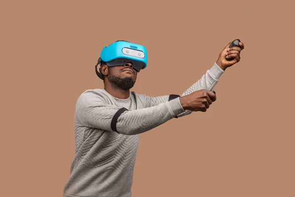 Black man wearing 3d vr glasses, playing videogame, holding joystick in hands