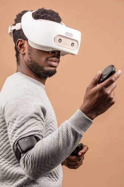 Black man wearing 3d vr glasses, playing videogame, holding joystick in hands