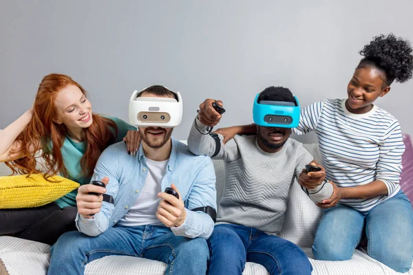 Twee jongens spelen video-games met behulp van Vr bril en vriendinnen steunen hen. — Stockfoto