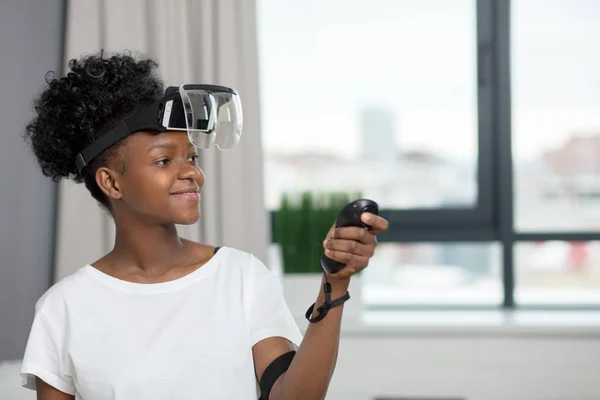 Africká žena sledování videa pomocí Vr brýle s dálkovým ovládáním doma. — Stock fotografie