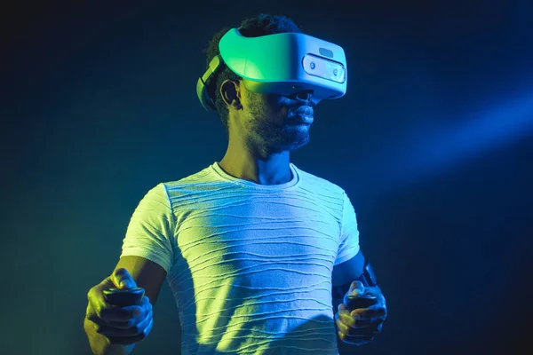 Uomo africano in bianco, indossando VR Headset su sfondo verde blu doppio colore . — Foto Stock