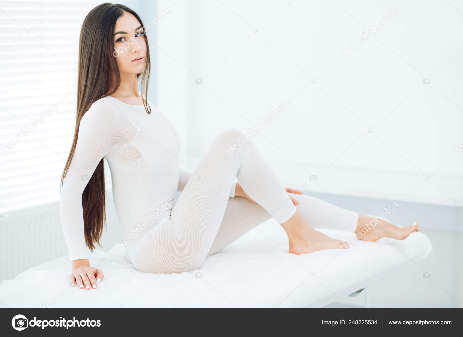 Young brunette woman in white slimming bodysuit waiting for LPG