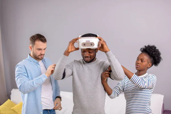 Multicultural friends help african guy to manade with vr headset for fist time