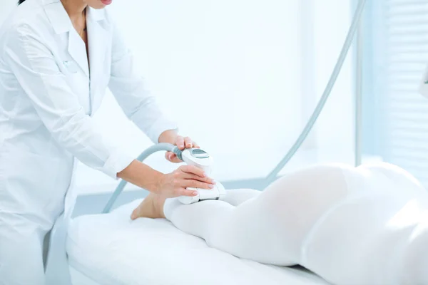 Женская клиентка клиники красоты получает массаж сжиженного нефтяного газа на ногах для поднятия тела — стоковое фото