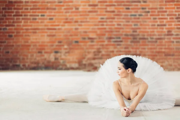Vackra ballerina gör sträcktiderna liggande på golvet — Stockfoto